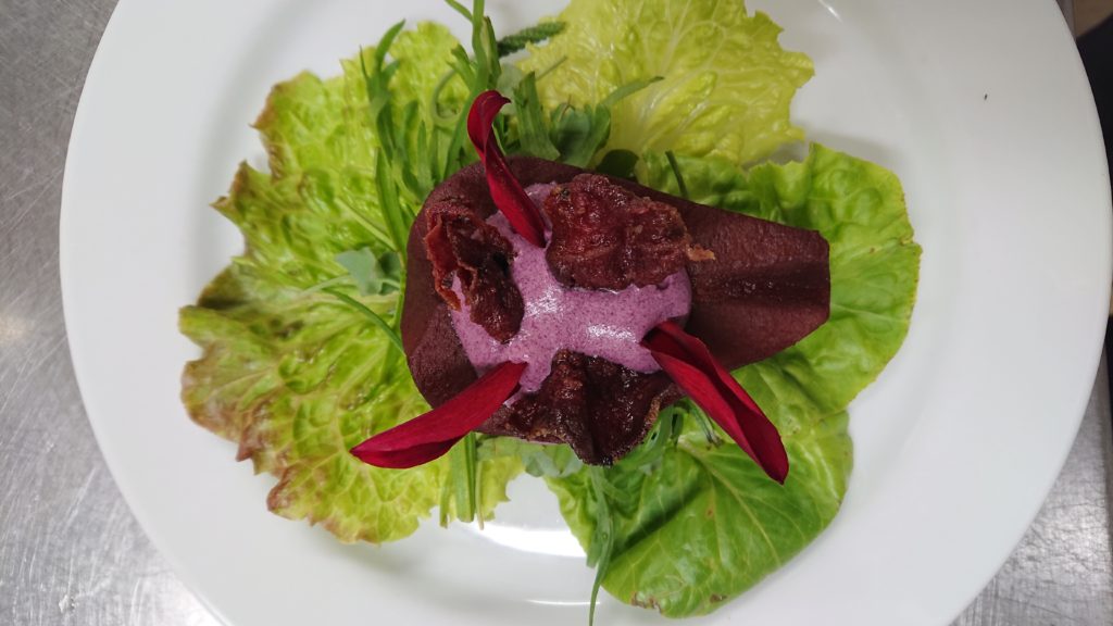 Ein Teller mit einer vegetarischen Vorspeise, Rotwein-Birne mit Holunder-Sahne-Schaum.